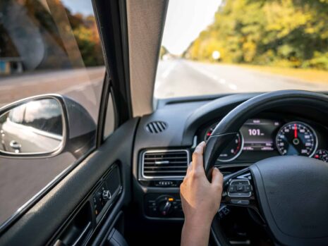 Woman driver's hands on the steering wheel inside the car.